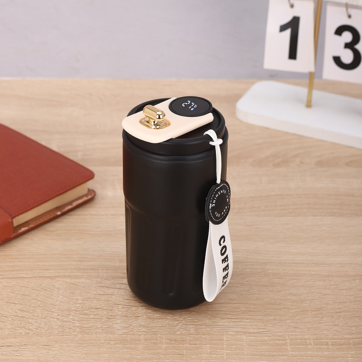 Black coffee thermos with digital display on a wooden surface.