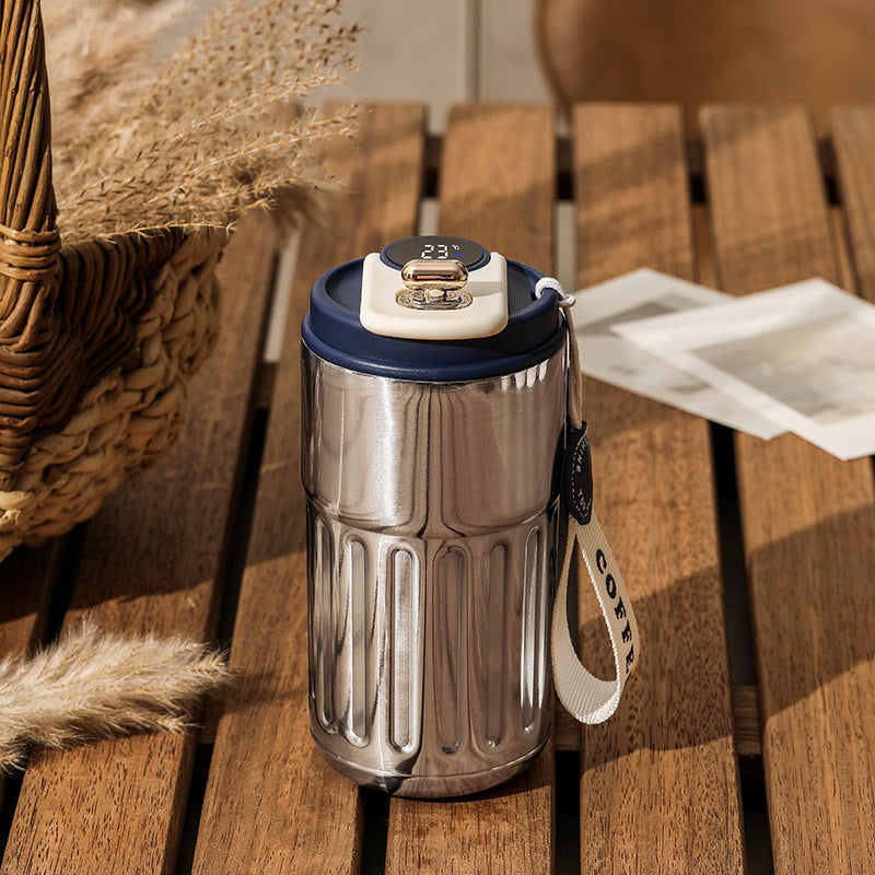 Silver tumbler with a blue lid on a wooden table.