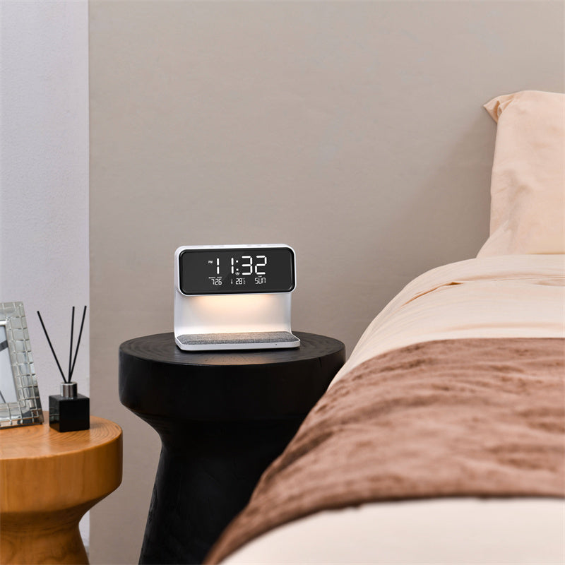 Alarm clock on a nightstand next to a bed.