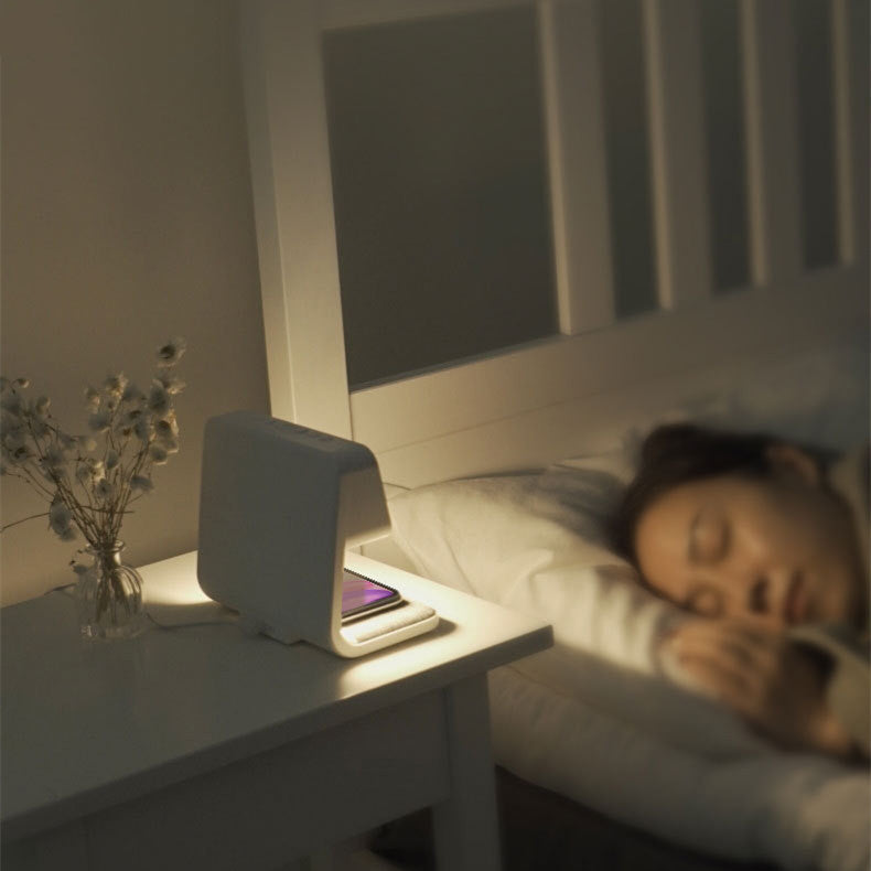 Woman sleeping in bed with a nightstand lamp and phone on a nightstand.