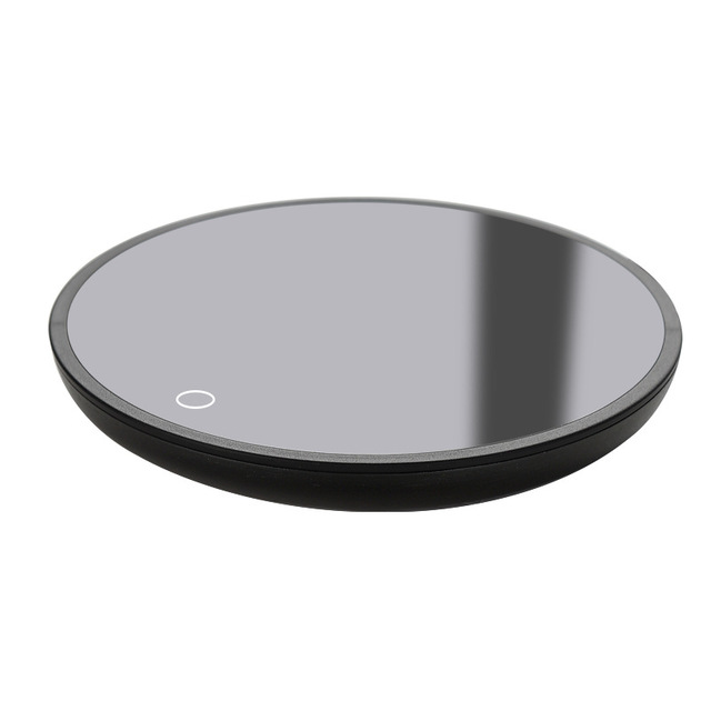Round black electronic device with a reflective surface on a white background.