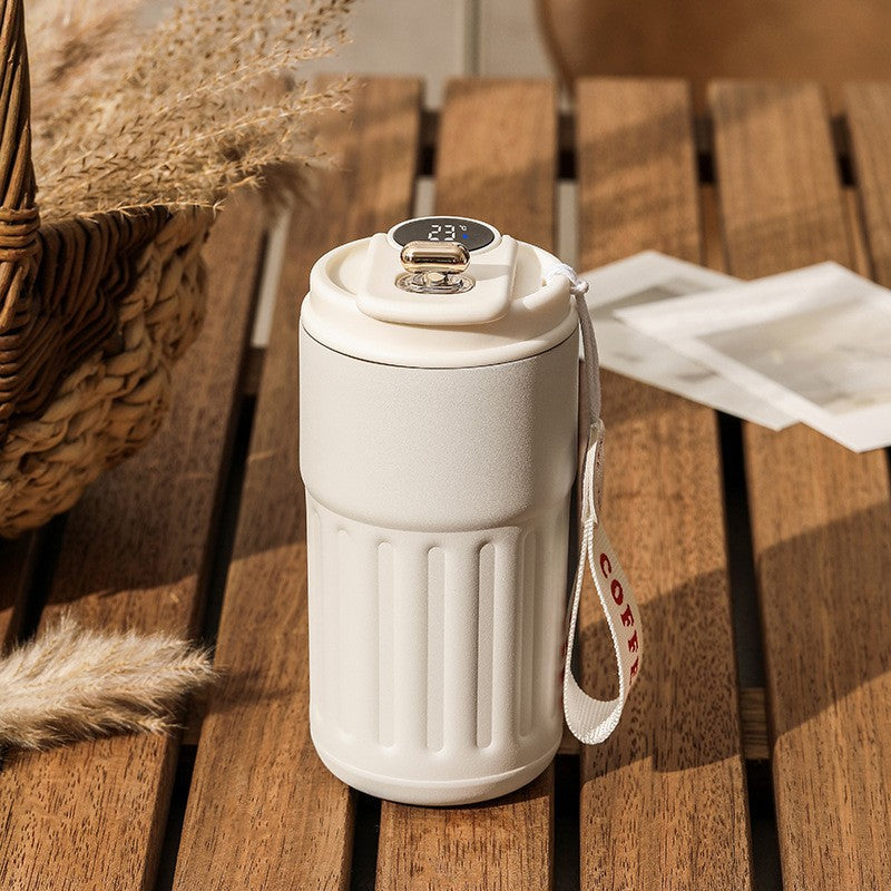 White thermos with digital display on a wooden surface.