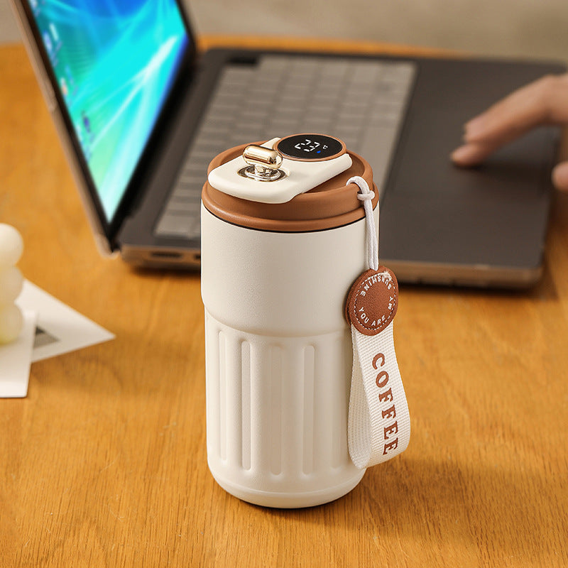 White coffee thermos on a desk with a laptop in the background.
