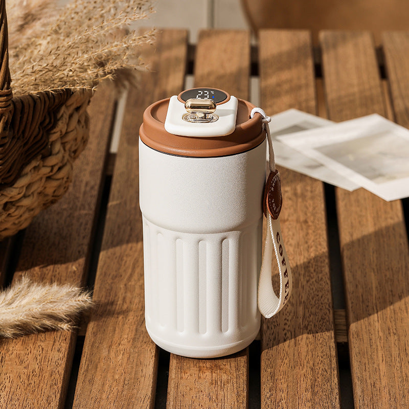 White travel mug with brown lid on a wooden surface.