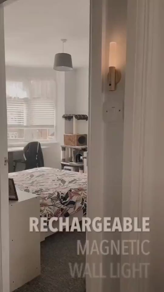 Wall-moounted LED lamp being removed from wall and held in hand while illuminating a book.