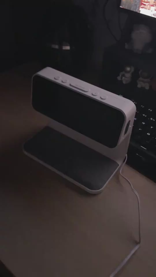 Table lamp in dark being turned on with phone placed for charging and clock activated.