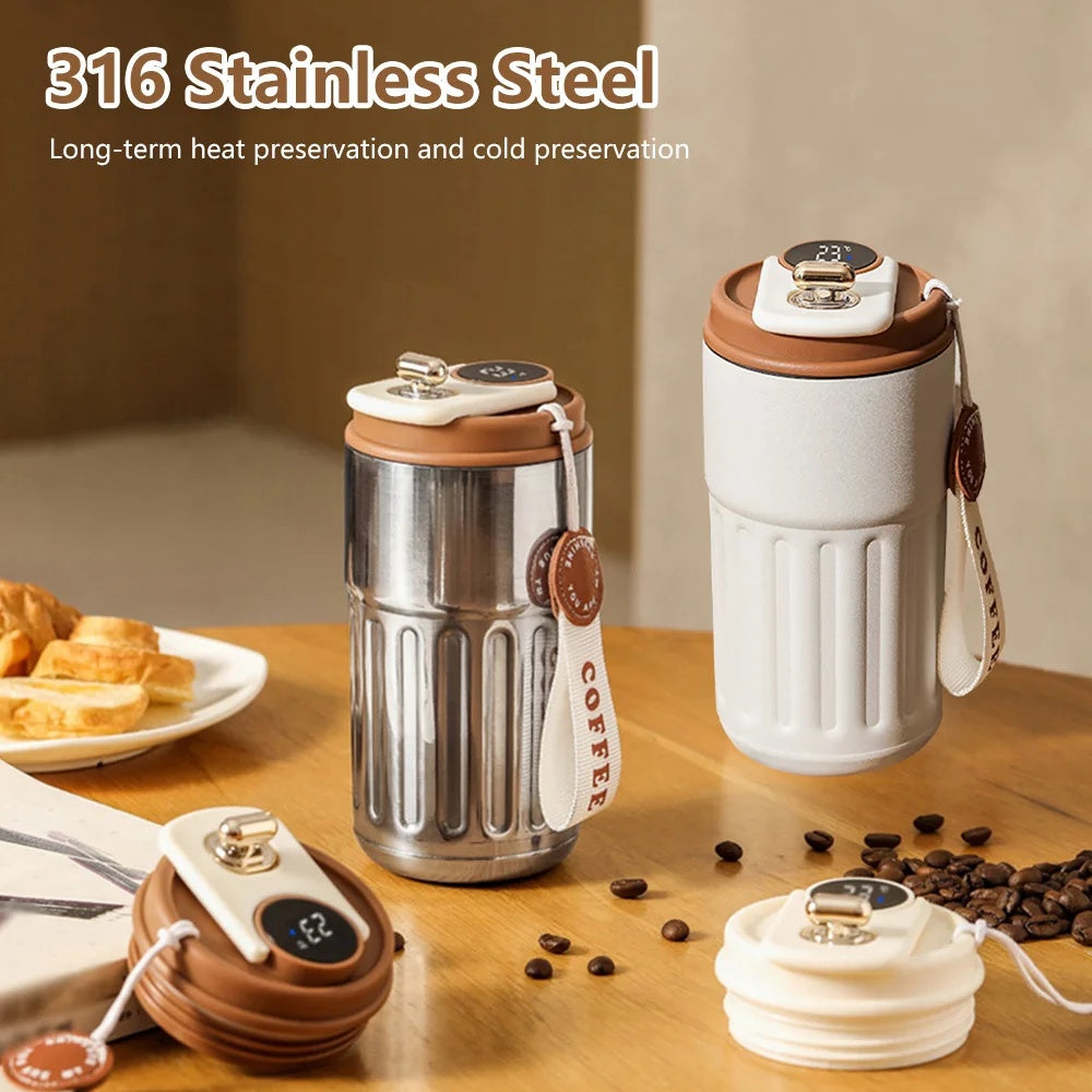 Two stainless steel coffee tumblers on a wooden table with coffee beans and a plate of pastries.