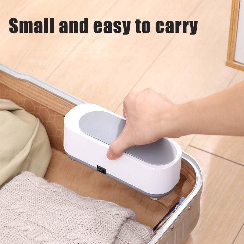 Hand holding a small ultrasonic cleaning device under a bed with text «Small and easy to carry».