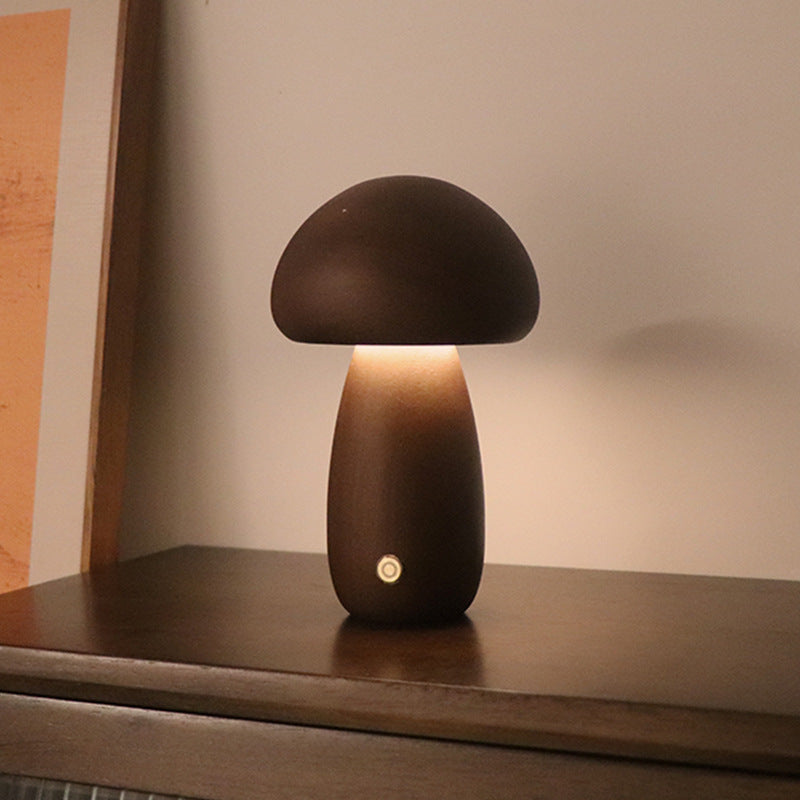 Walnut mushroom-shaped lamp on a wooden surface with warm glow.