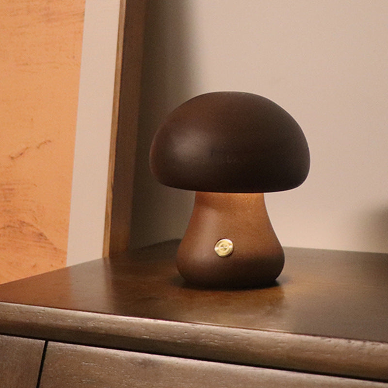 Walnut mushroom-shaped lamp on a wooden surface with warm glow.