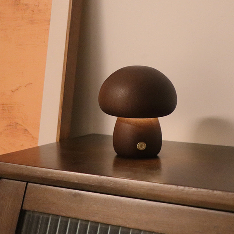Walnut mushroom-shaped lamp on a wooden surface with warm glow.